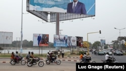 ARCHIVES - Des motocyclistes passent devant des panneaux de campagne dans une rue de Lomé, au Togo, le 19 février 2020.