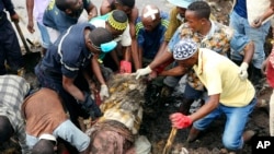Locals and rescuers retrieve a mattress from a site where two houses were crushed by the collapse of a massive, sprawling dumpsite when rains poured in Pemba city on the northeastern coast of Mozambique, Monday, April, 29, 2019.