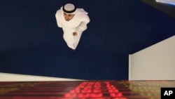An Emirati trader checks the stocks on the screen at the Dubai Financial Market in Dubai, United Arab Emirates, Sunday, March 8, 2020.