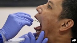 A man has his nasal swab sample collected by a health worker during a mass test for the new coronavirus at the local district office in Tanah Abang in Jakarta, Indonesia, June 21, 2020.