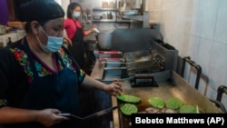 Natalia Méndez cooks a meal with pork chops, Jalapenos and cactus plants in the kitchen of La Morada, an award winning Mexican restaurant she co-owns with her family in South Bronx, Wednesday Oct. 28, 2020, in New York. (AP Photo/Bebeto Matthews)