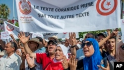 Warga berunjuk rasa membentangkan spanduk bertuliskan “Ayat al-Quran, sebelum peraturan lain” dalam unjuk rasa menentang usulan kesetaraan gender yang diajukan pemerintah, di Tunis, Sabtu, 11 Agustus 2018.