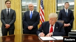 U.S. President Donald Trump, flanked by Senior Advisor Jared Kushner (standing, L-R), Vice President Mike Pence and Staff Secretary Rob Porter welcomes reporters into the Oval Office for him to sign his first executive orders at the White House in Washington.