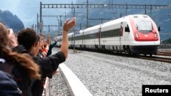Des invités saluent le train qui vient de passer dans le tunnel nommé NEAT Gotthard Base Tunnel, près de Erstfeld, en Suisse, le 1er juin 2016. 