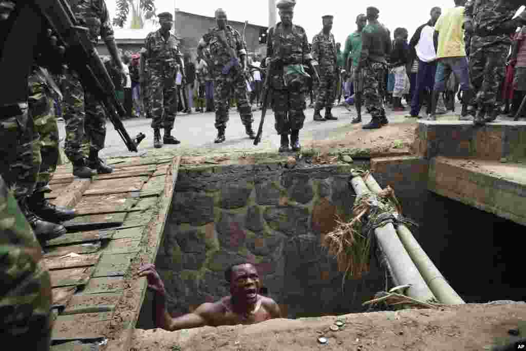 Jean Claude Niyonzima pleads with soldiers to protect him from a mob of demonstrators after he emerged from hiding in a sewer in Bujumbura, May 7, 2015