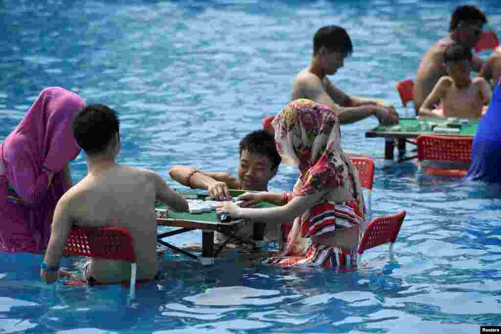People sit in water and play mahjong at a water park on a hot day in Chongqing, China.