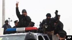 An Iraqi riot police officer flashes the V-sign as his unit returns to its headquarters from clashes between Iraqi army and al-Qaida fighters Basra, Iraq's second-largest city, Jan. 5, 2014.