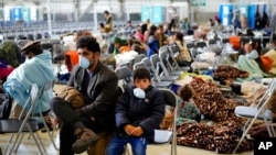 FILE - Evacuees from Afghanistan wait with other evacuees to fly to the United States or another safe location in a makeshift departure gate inside a hangar at the U.S. airbase in Ramstein, Germany, Sept. 1, 2021. 