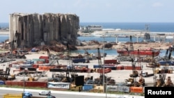 Des véhicules roulent près du silo à grains qui a été endommagé lors de l'explosion du port de Beyrouth, à Beyrouth, au Liban, le 9 avril 2021.