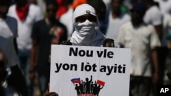A demonstrator carries the Creole message "We want a different Haiti" during a march led by the art community to continue demanding the resignation of Haitian President Jovenel Moise in Port-au-Prince, Haiti, Oct. 13, 2019. 