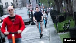 Para turis mengendarai skuter listrik untuk berkeliling kota Washington DC. 