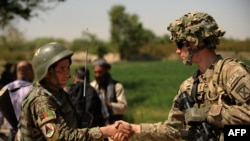 FILE - A U.S. soldier, right, shakes hands with an Afghan National Army soldier before the opening ceremony for a newly completed mosque in southern Kandahar province, April 1, 2011, where the U.S. is funding its rebuilding.