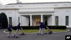 Workers walk with hand trucks past the West Wing of the White House, as offices in the White House complex are being packed up and moved out, Friday, Jan. 15, 2021, in Washington. (AP Photo/Gerald Herbert)