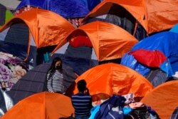 FILE - Tents used by migrants seeking asylum in the United States line an entrance to the border crossing, March 1, 2021, in Tijuana, Mexico.