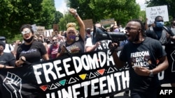 FILE - Demonstrators take part in a Juneteenth march and rally in downtown Washington, June 19, 2020.
