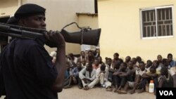 Polisi berjaga-jaga sementara massa menunggu di luar pengadilan di Kaduna, Nigeria (20/4).