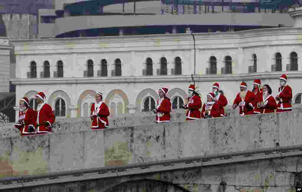 People dressed in Santa Claus costumes run across a bridge during a Santa Claus Race in Macedonia&#39;s capital Skopje, Dec. 25, 2016.