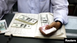 A man counts US dollars and Burma kyats at a money changer in Rangoon, March 21, 2012. 