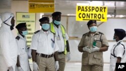 FILE - In Aug. 4 file photo, Nigerian port health officials wait to screen passengers at the arrivals hall of Murtala Muhammed International Airport in Lagos. 