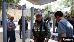 Seorang petugas polisi perbatasan Israel bertanya untuk memeriksa identitas seorang pria Palestina di sebelah pendeteksi metal yang baru di pasang di kawasan yang dikenal kaum Muslim sebagai Haram al-Sharif dan Temple Mount untuk umat Yahudi sebelum dibuka kembali di Kota Tua Jerusalem, 16 Juli 2017 (foto: REUTERS/Ronen Zvulun)