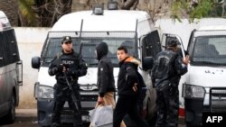 Des garçons tunisiens passent devant les forces de sécurité qui montaient la garde dans la ville de Tebourba, dans le nord du pays, le 11 janvier 2018