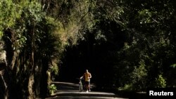 FILE - A man walks with his bicycle through the Tijuca Forest in Rio de Janeiro, Brazil, July 29, 2012.