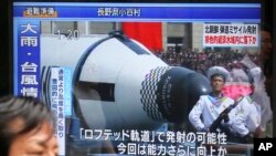 Seorang pria berjalan melintasi layar TV publik di Tokyo, yang menyiarkan berita peluncuran rudal balistik Korea Utara yang mendarat di perairan zona ekonomi Jepang, Selasa, 4 Juli 2017. (Foto: AP Photo/Shizuo Kambayashi)