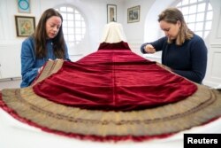 Des membres de la Royal School of Needlework travaillent sur la robe d'État du roi Charles, qu'il portera lors de son couronnement le 6 mai, au palais de Hampton Court, à East Molesey, en Grande-Bretagne, le 27 février 2023.