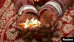 Seorang pengantin perempuan memegang bunga dengan tangannya dihiasi pasta henna selama upacara pernikahannya di kota Ahmedabad, India barat, 22 Januari 2012. (Foto: Reuters)