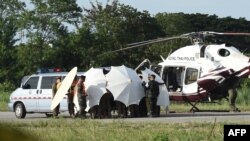 Police and military personnel use umbrellas to cover around a stretcher near a helicopter and an ambulance at a military airport in Chiang Rai on July 9, 2018, as rescue operations continue for those still trapped inside the cave in Khun Nam Nang Non Fore