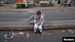 A child sits along a road median as he eats his breakfast of a single piece of "roti" (South Asian bread) while waiting for work in Karachi early morning May 6, 2012.