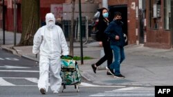 Žena u zaštitnom odelu izlazi iz prodavnice u Kvinsu, u Njujorku (Foto: AFP/Johannes Eisele)