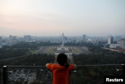 A girl looks on National Monument (Monas) as smog covers the capital city of Jakarta, Indonesia, July 4, 2019. REUTERS/Willy Kurniawan