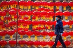A man wearing a face mask to protect against the spread of the coronavirus walks past a display of lanterns at a public park in Beijing, Jan. 5, 2021.