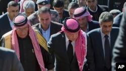 Raja Yordania, Abdullah II (tengah), didampingi Safi al-Kaseasbeh (kiri), ayah dari pilot Yordania yang dibunuh ISIS, Lt. Muath al-Kaseasbeh, dan paman pilot itu Fahed al-Kaseasbeh, tiba di tempat acara memorial di desa Ai, dekat Karak (5/2). (AP/Nasser Nasser)