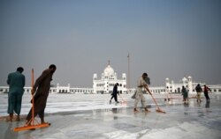 Workers clean the floor at the Shrine of Baba Guru Nanak Dev at the Gurdwara Darbar Sahib ahead of its opening in the Pakistani town of Kartarpur near the Indian border, Nov. 6, 2019.