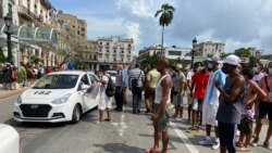 People gather near police cars during protests against and in support of the government, amidst the coronavirus disease (COVID-19) outbreak, outside the Capitol building, in Havana, Cuba, July 11, 2021.