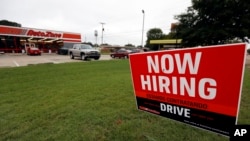 FILE- A bilingual help wanted sign for Auto Zone, a retailer of aftermarket automotive parts and accessories, is posted outside the store in Canton, Miss., Sept. 27, 2018.