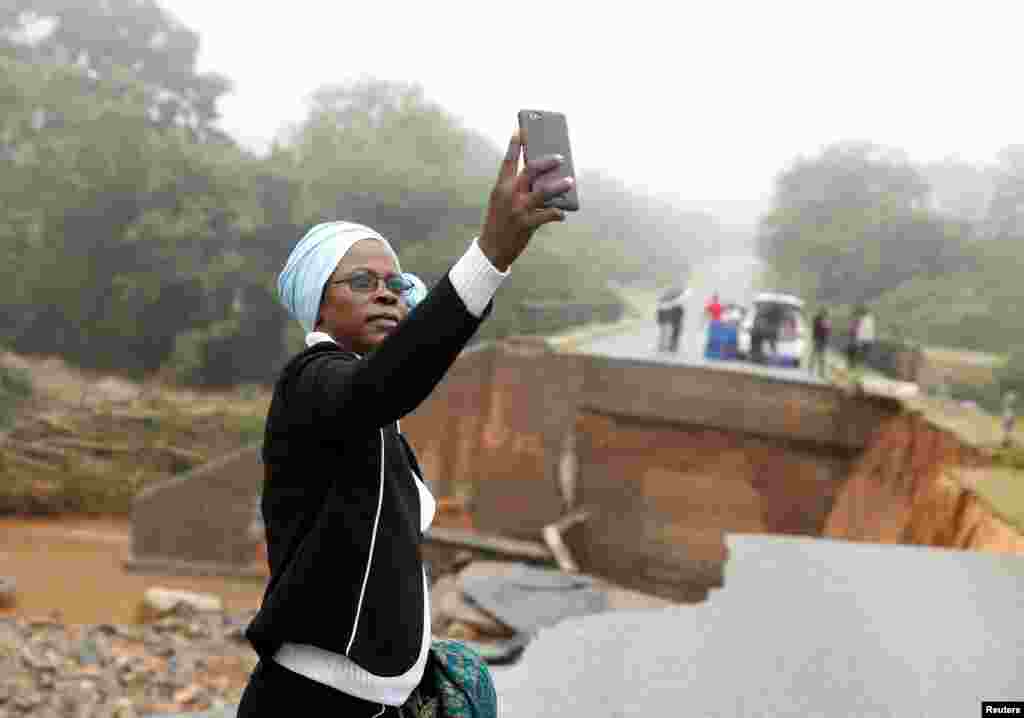 ស្រ្តីម្នាក់ថតរូបជាមួយនឹងស្ពានដែលត្រូវបានទឹកទន្លេ Umvumvu បំបាក់បន្ទាប់ពីខ្យល់កួច Idai ក្នុងទីក្រុង Chimanimani ប្រទេសស៊ីមបាវ៉េកាលពីថ្ងៃទី១៨ ខែមីនា ឆ្នាំ២០១៩។&nbsp;