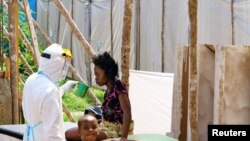 20일 시에라 리온에서 의료구호요원이 보호장비를 착용하고 에볼라 환자에게 물을 권하고 있다