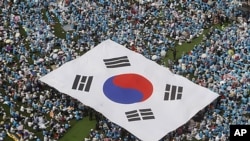 FILE - People carry a large scale South Korean national flag during an anti-North Korea rally marking Memorial Day in Seoul, June 6, 2011. South Korea’s National Counter Terrorism Center raised the country’s terror watch level to 'alert' status, May 2, 2024.