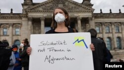 A person holds a placard reading "Solidarity with women in Afghanistan" during a protest against support for the Taliban, in front of the lower house of parliament, the Bundestag, in Berlin, Germany, Aug. 17, 2021.