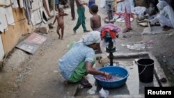 FILE - A woman who says she belongs to the Rohingya community from Myanmar, washes clothes in a New Delhi camp, September 13, 2014.
