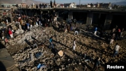 Warga Pakistan memeriksa lokasi ledakan di kawasan warga Syiah di Quetta yang menewaskan sedikitnya 80 orang (16/2). 