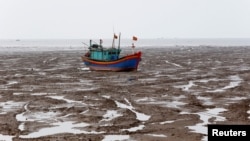 A fishing boat is seen during the low tide at the beach in Thanh Hoa province, Vietnam June 4, 2018.