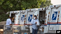 Postal workers load packages in their mail delivery vehicles at the Panorama city post office on Aug. 20, 2020 in the Panorama City section of Los Angeles.