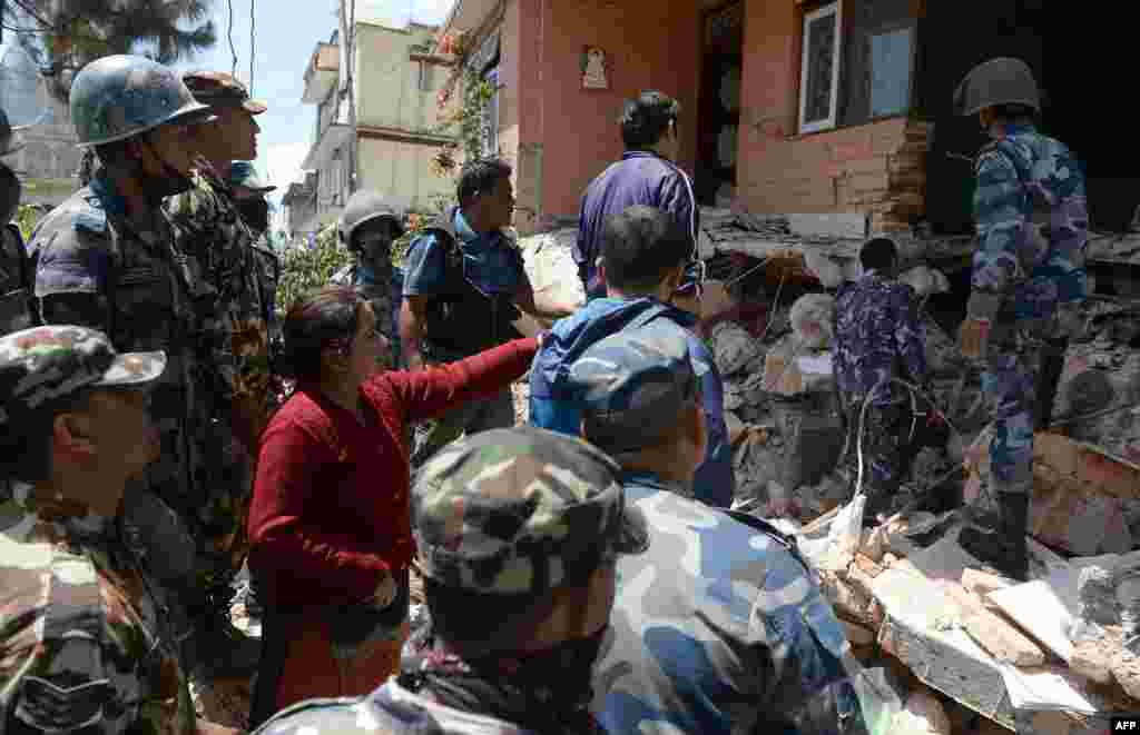 Warga Nepal Sangita Mahat (tengah) mengarahkan polisi saat mereka mengambil mayat &nbsp;salah satu kerabatnya Prasamsah, 14, dalam upaya penyelamatan di Balaju, Kathmandu (27/4). ​(AFP/Prakash Singh)