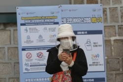 A woman wearing a face mask watches her smartphone in Seoul, South Korea, Saturday, March 21, 2020.