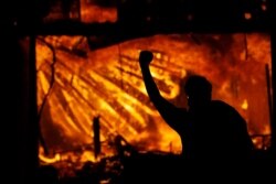 A protester gestures in front of the burning 3rd Precinct building of the Minneapolis Police Department on Thursday, May 28, 2020, in Minneapolis.