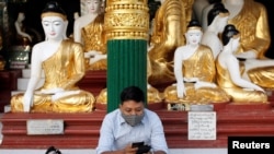A man wears a face mask as he uses his phone at Shwedagon Pagoda in Yangon, Myanmar January 31, 2020. REUTERS/Ann Wang